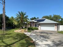 Charming single-story home with a lush, landscaped front yard and a white two car garage at 652 N Elm St, Englewood, FL 34223