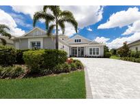 Beautiful, light grey two-story home with a large palm tree and paved driveway at 8133 Grande Shores Dr, Sarasota, FL 34240