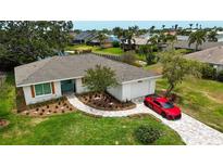 Charming single-story home featuring a lush lawn, a paver walkway, and a red sports car in the driveway at 8808 44Th Avenue W Dr, Bradenton, FL 34210