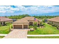Stunning single-story home with a tile roof, three-car garage, and a lush, manicured lawn at 20359 Cristoforo Pl, Venice, FL 34293