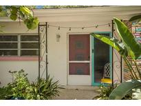 Charming home entrance with decorative screen door, teal accents, and lush tropical landscaping at 2207 Hickory Ave, Sarasota, FL 34234