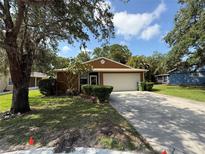 Charming single-story home with a well-manicured lawn, mature trees, and a spacious driveway leading to an attached garage at 3957 Bearded Oaks Ct, Sarasota, FL 34232