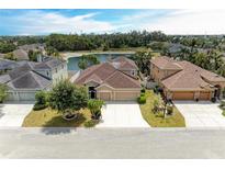 An aerial view shows a tan two-story home with a three-car garage and a private lake in the backyard at 4211 30Th E Ln, Bradenton, FL 34208