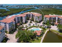 An aerial view of the condo complex featuring a pool, lush landscaping, and waterfront views at 5430 Eagles Point Cir # 101, Sarasota, FL 34231
