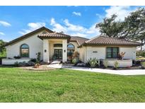 Charming single-story home featuring a tile roof and a beautifully landscaped front yard with fresh green grass at 8950 Misty Creek Dr, Sarasota, FL 34241