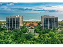 Stunning aerial view of beachfront condos with manicured grounds and direct access to a beautiful sandy beach at 1241 Gulf Of Mexico Dr # 803, Longboat Key, FL 34228