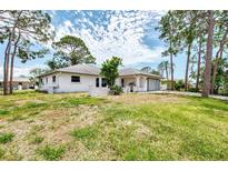 Single story home with a large front yard, an attached garage, and a white exterior at 1271 Nantucket Rd, Venice, FL 34293