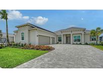 Charming home featuring a brick driveway, well-manicured lawn, attached two-car garage and beautiful landscaping at 17449 Sandpearl Rd, Venice, FL 34293