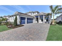 Charming home featuring a manicured lawn, lush plantings, and a spacious driveway leading to a two-car garage at 17927 Palmiste Dr, Bradenton, FL 34202