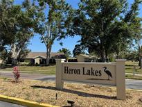 The Heron Lakes community sign with manicured landscaping and mature trees at 3002 Sail Pointe Cir # 1B, Venice, FL 34293