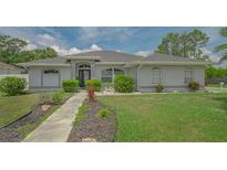 Charming single-story home with manicured lawn and lush landscaping, creating inviting curb appeal at 4037 Wooley Ave, North Port, FL 34287