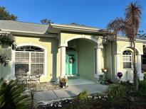 Charming home featuring a welcoming turquoise front door, columns, and decorative landscaping at 4217 N Chamberlain E Blvd, North Port, FL 34286