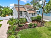 Charming two-story home with lush landscaping, a white fence, and a brick paver driveway at 748 Soundview Dr, Palm Harbor, FL 34683