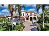 Elegant two-story home featuring a red tile roof, arched entrance, and lush tropical landscaping at 8016 Bounty Ln, Bradenton, FL 34202