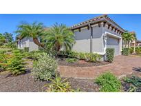 Landscaped yard with well-maintained shrubs, trees, and a brick path leading to the home, creating an inviting curb appeal at 12619 Sorrento Way, Bradenton, FL 34211