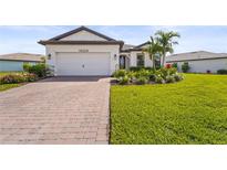 Charming single-Gathering home featuring a well-manicured lawn, paver driveway, and an attached two-car garage at 16226 Hidden Oak Loop, Lakewood Ranch, FL 34211
