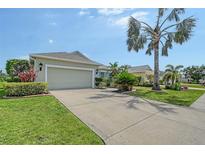 Charming single-story home featuring a well-manicured lawn, palm trees, and a spacious driveway leading to an attached two-car garage at 5320 Tide Point Way, Bradenton, FL 34208