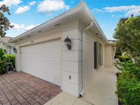 A single-Gathering house with a brick driveway, white garage door, exterior lights and lush landscaping at 7641 Quinto Dr, Sarasota, FL 34238