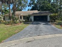 Charming single-story home with well-manicured lawn and mature trees enhancing its curb appeal at 2181 Pine Gardens Trl, Sarasota, FL 34231