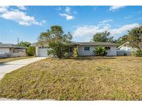 Single-story home with an attached garage and a front lawn under a bright, cloudy sky at 2606 Bismark Way, Sarasota, FL 34231