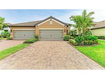 Paver driveway leading to a two-car garage with well-maintained landscaping and a lush lawn at 4416 Amalfi Ave, Sarasota, FL 34243