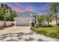Charming two-story home featuring a manicured front yard, mature trees, and an attached two-car garage at 5561 Burnt Branch Cir, Sarasota, FL 34232