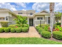 Beautifully landscaped single Gathering home with beige exterior, palm trees, and brick paver walkway at 6470 Indigo Bunting Pl, Lakewood Ranch, FL 34202