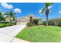Charming single-story home with a well-manicured lawn and lush landscaping, including palm trees at 8408 Whispering Woods Ct, Lakewood Ranch, FL 34202