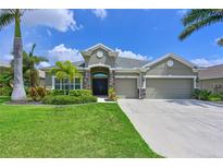 Charming single-story home with well-manicured lawn, mature landscaping, and three-car garage at 11342 77Th E St, Parrish, FL 34219