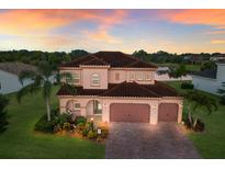 Elegant two-story home featuring a tile roof, arched entryway, and lush landscaping at 13706 American Prairie Pl, Lakewood Ranch, FL 34211