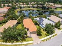 Stunning aerial view of a home with a tile roof, surrounded by lush landscaping and a serene lake at 14325 Stirling Dr, Lakewood Ranch, FL 34202