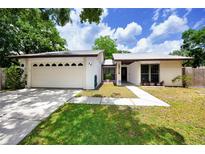 Charming single-story home featuring a well-manicured lawn, two-car garage and inviting front entrance at 15718 Squirrel Tree Pl, Tampa, FL 33624