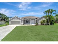 Charming single-story home boasts a manicured lawn and mature palm trees at 168 Wading Bird Dr, Venice, FL 34292