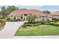Beautiful single-story home with a terracotta roof, manicured landscaping, and a circular driveway at 431 Fieldstone Dr, Venice, FL 34292