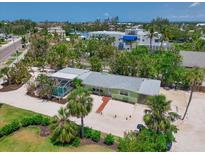 Charming home with a screen enclosed pool surrounded by lush tropical landscaping and a white gravel driveway at 5924 Gulf Of Mexico Dr, Longboat Key, FL 34228
