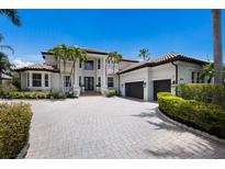 Stately home featuring a barrel tile roof, lush tropical landscaping, and a paver driveway leading to a two-car garage at 6919 Westchester Cir, Lakewood Ranch, FL 34202
