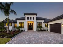 Modern home featuring a well-manicured front yard, a paver driveway, and neutral-toned stucco at 8563 Sea Mist Loop, Sarasota, FL 34240