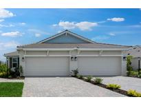 Beige home featuring a two-car garage and beautifully landscaped front yard at 16234 Isola Pl, Bradenton, FL 34211