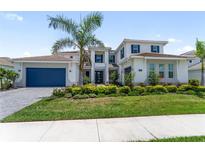 Beautiful two-story home with a well-manicured lawn, blue shutters, and a dark blue garage door at 18215 Cayo Largo Pl, Bradenton, FL 34202