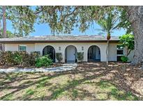 Charming home exterior featuring arched entryways, a tiled roof, and mature landscaping with shade trees at 415 Courbet Dr # 415, Nokomis, FL 34275