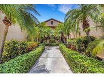 Inviting condo exterior featuring lush landscaping and palm trees lining the walkway to the entrance at 5632 Ashton Lake Dr # 5632, Sarasota, FL 34231