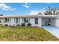 Charming single-story home featuring a bright blue door, light blue shutters, and a well-maintained front lawn at 577 Circlewood Dr # X7, Venice, FL 34293