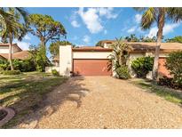 Charming villa featuring a well-manicured lawn, gravel driveway, and a two-car garage at 6203 Courtside Dr # 21, Bradenton, FL 34210