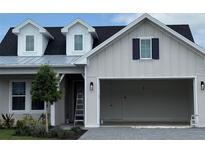 Charming home exterior featuring light siding, a dark roof, dormer windows, and an attached two-car garage at 650 Maldives Trl, Sarasota, FL 34234