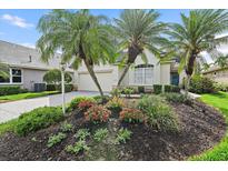 Charming single-story home featuring lush landscaping with palm trees and colorful flower beds adding curb appeal at 7821 Troon Ct, Lakewood Ranch, FL 34202