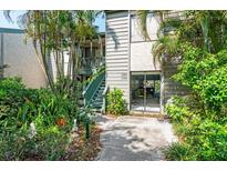 Multi-level condo with lush landscaping, a wooden staircase, and a pathway to the entrance at 1629 Pelican Cove Rd # 138A, Sarasota, FL 34231