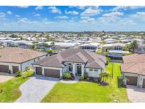 Beautiful single-story home with a well-manicured lawn, dark brown tiled roof, paver driveway and an attached three-car garage at 4312 Vasco St, Punta Gorda, FL 33950