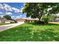 Charming single-story home with a lush green lawn, mature shade tree, and well-maintained landscaping at 6011 91St E St, Bradenton, FL 34202