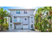 Two-story home exterior featuring light blue siding, a balcony with blue chairs, and lush tropical landscaping at 6250 Holmes Blvd # 63, Holmes Beach, FL 34217