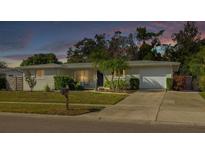 Charming single-story home with a well-manicured lawn and mature landscaping at dusk at 6442 Colonial Dr, Sarasota, FL 34231